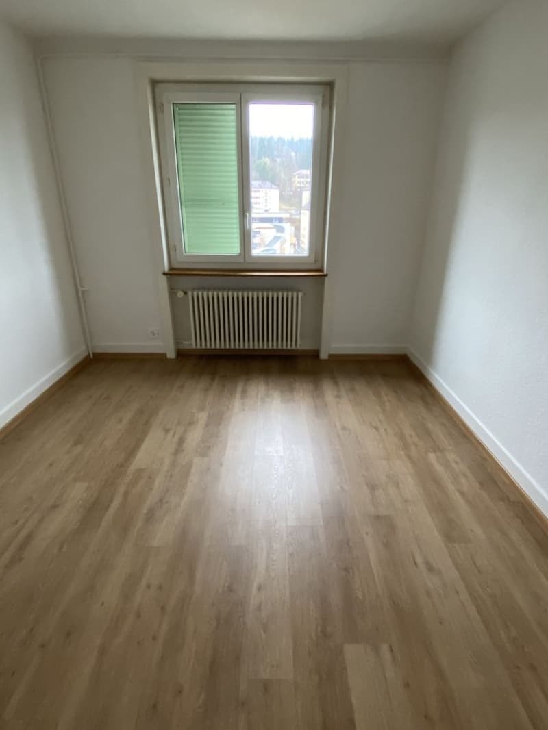 empty room, wooden floor, white walls, window with green shutters, radiator