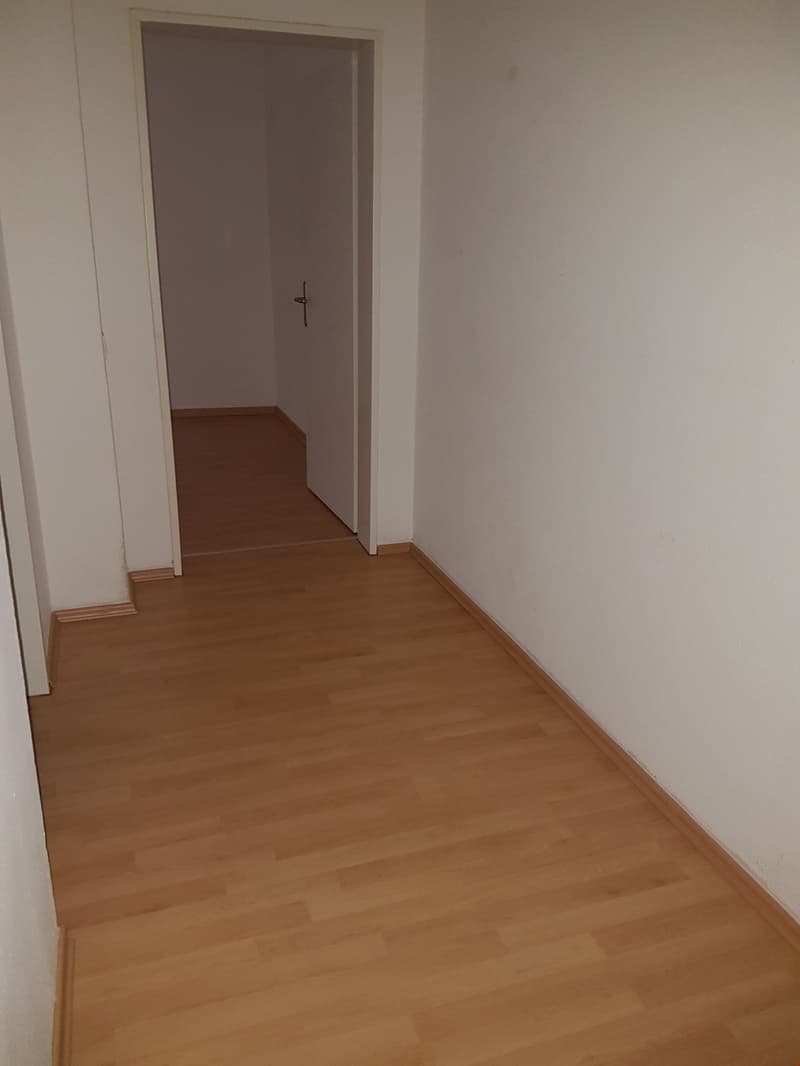 an empty hallway with wooden floor and white walls
