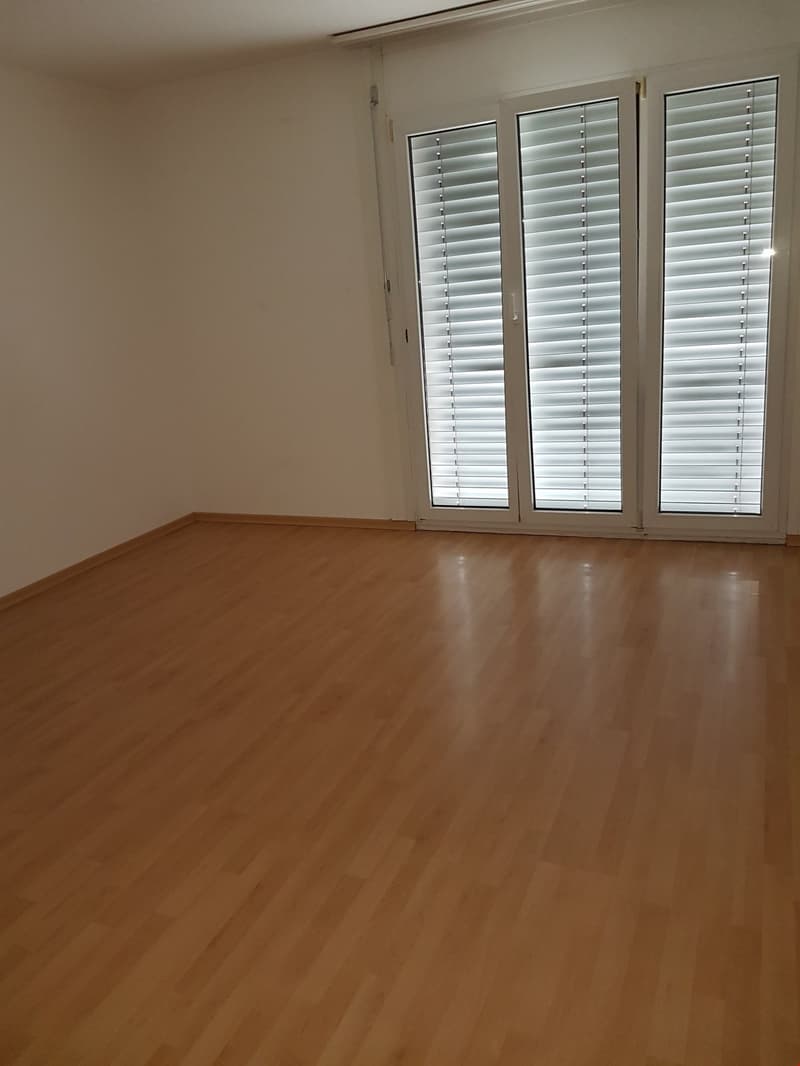 Empty room with wooden flooring, glass doors, and white walls