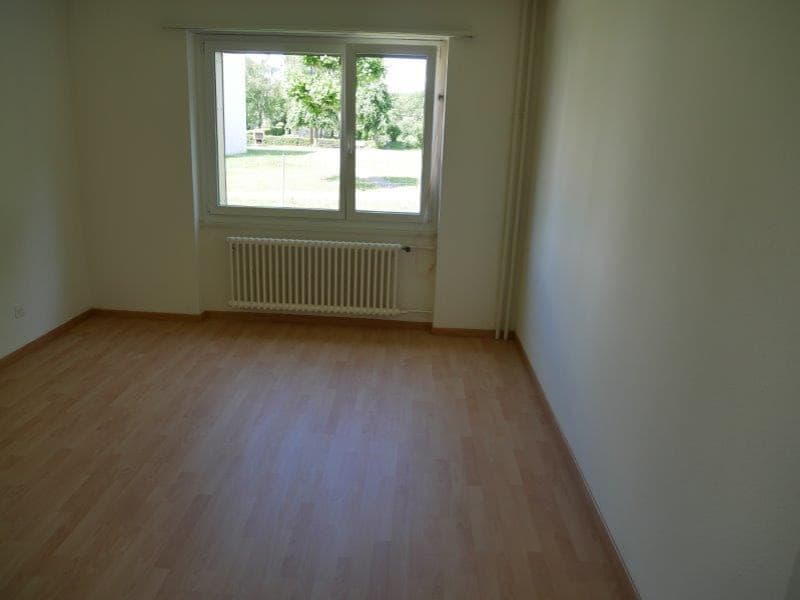 Empty room with white walls, wooden floor, window with a view of the outside, white radiator.
