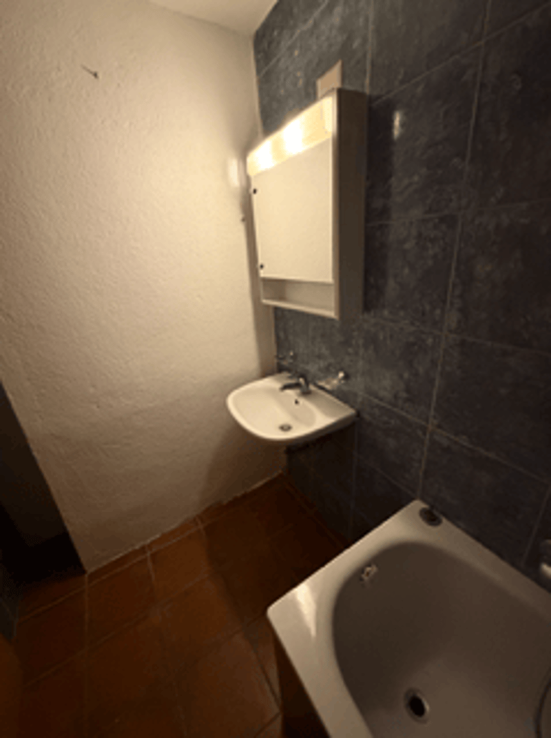 Small bathroom with sink, bathtub, and white wall