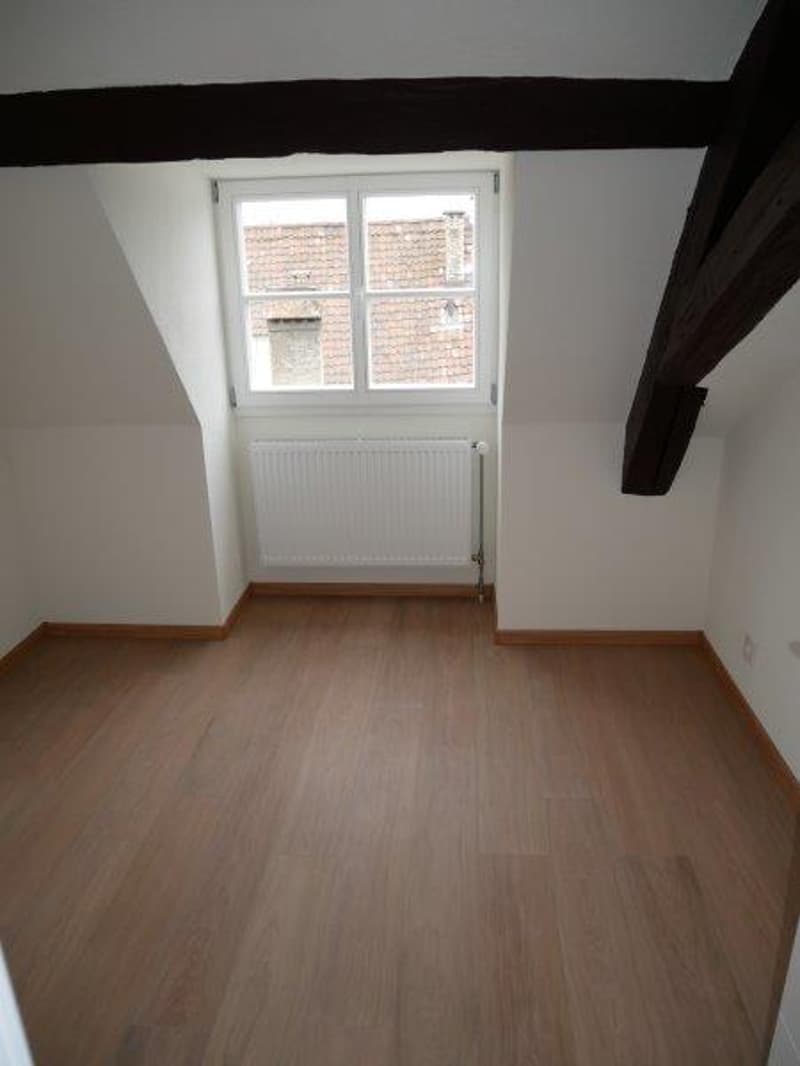 Empty room, wooden floor, white walls, window, radiator