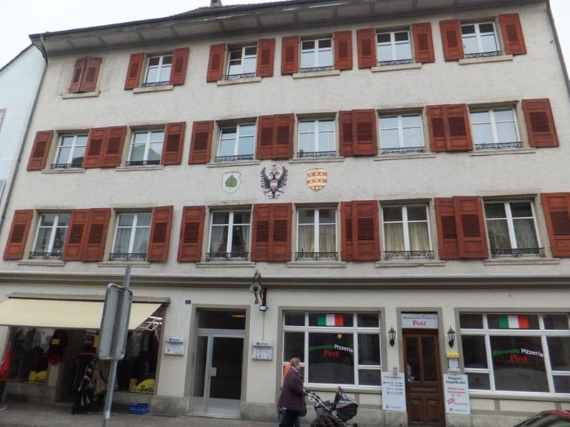 white facade, red shutters, coat of arms, multiple floors, restaurants below