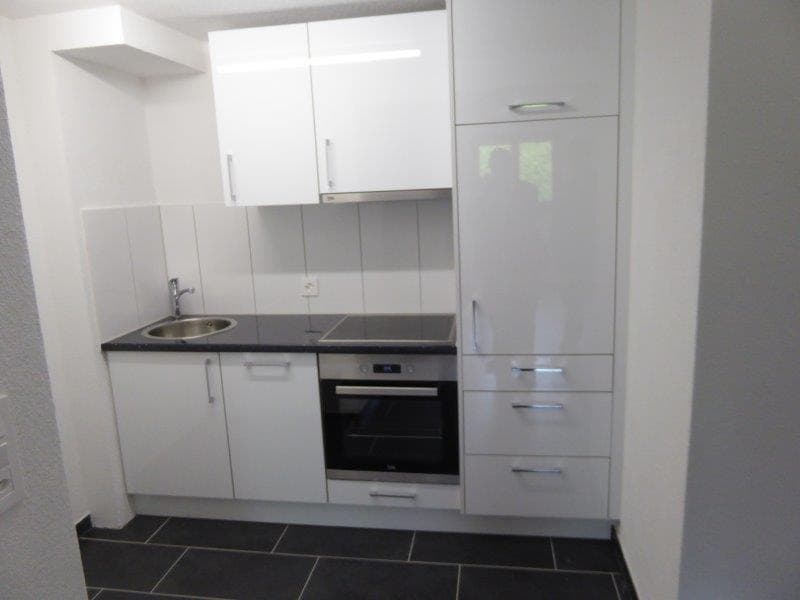 Modern kitchen with white cabinetry, tiled flooring, a sink with a faucet, a built-in oven, and a dishwasher.