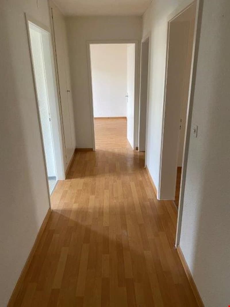 empty hallway with light brown wood floors and white walls