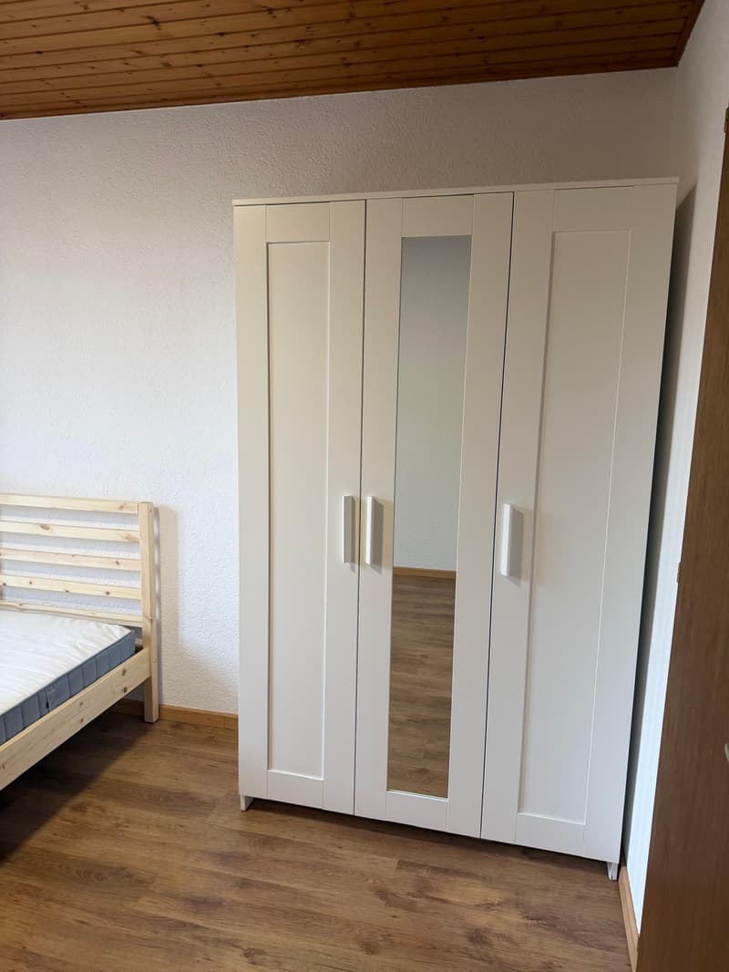 empty room with white wardrobe, wooden bed, wooden floor, white wall