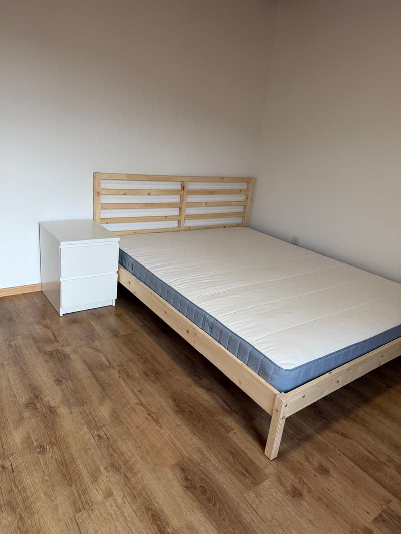 room with wooden floor, white walls, bed, and nightstand