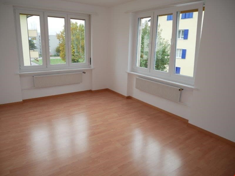 empty room, wooden floor, white walls, two large windows, white radiators