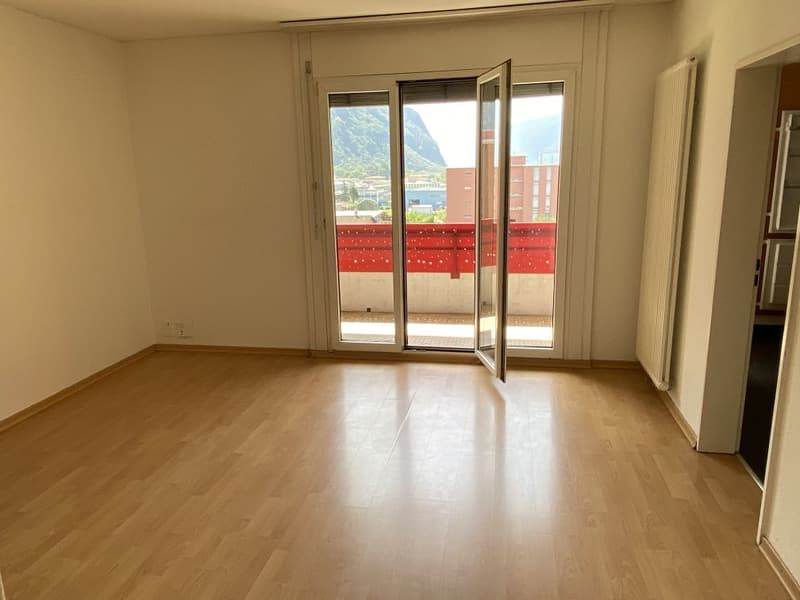 empty room, hardwood floors, sliding glass doors leading to balcony, heater, window, no furniture