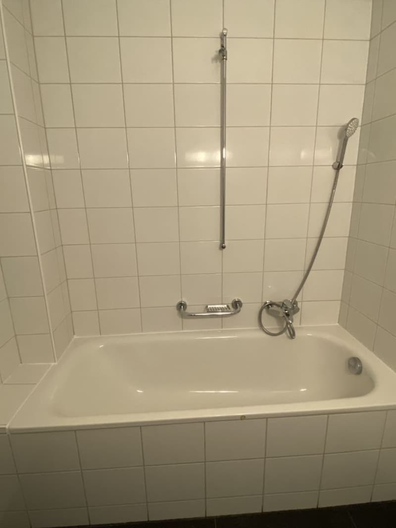 tiled walls, white bathtub, grab bars, shower