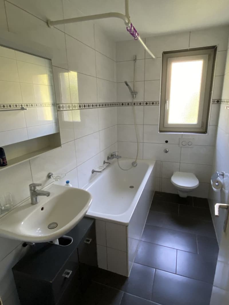 Bathroom with bathtub, sink, toilet, mirror, and window