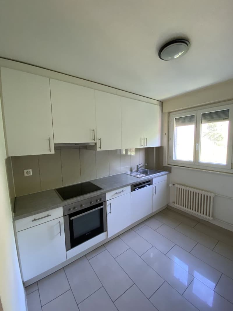 modern kitchen with white cabinets, tiled floor, stainless steel appliances, window with blinds, radiator