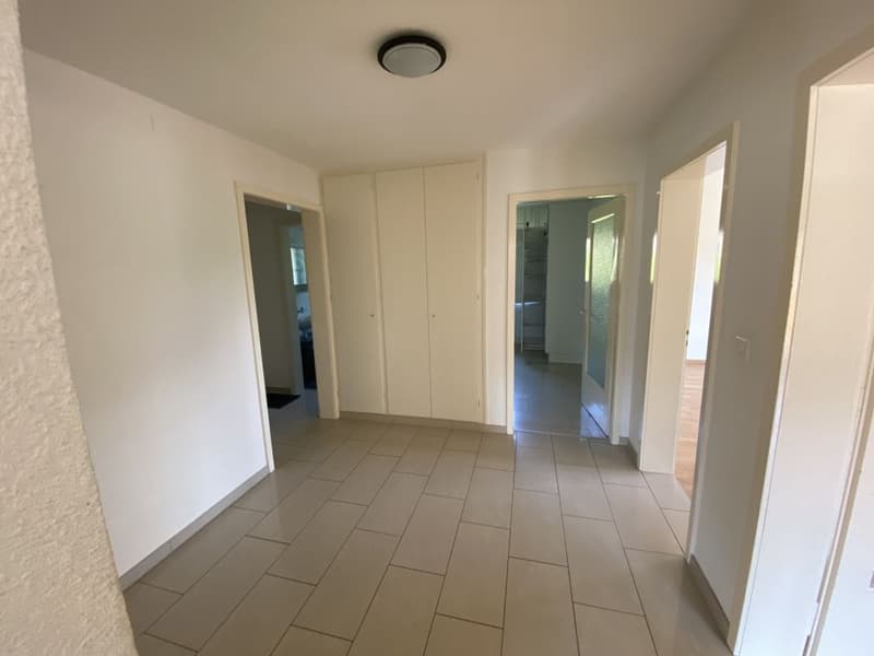Empty hallway with tiled floor, white walls, and doors leading to other rooms
