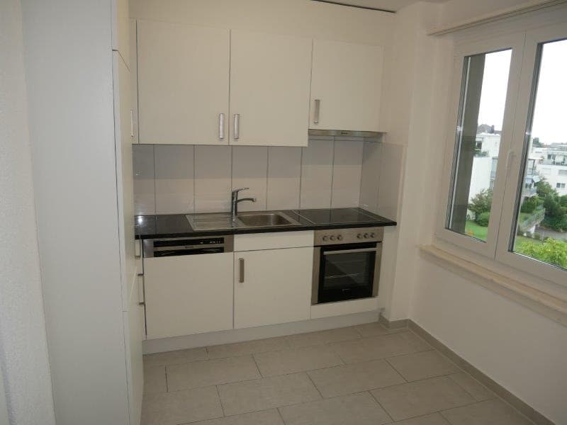 modern kitchen with white cabinets, black countertops, stainless steel sink, dishwasher, oven, and a window with a view