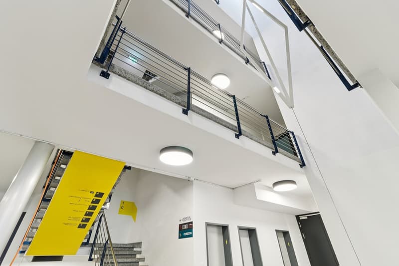 Multiple floors, yellow signs, metal railings, built-in lighting