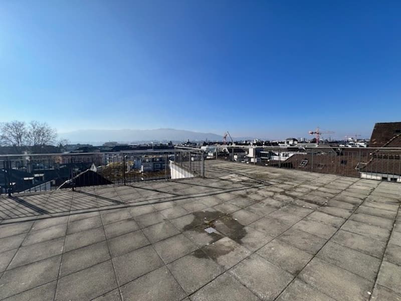 Empty rooftop terrace with city view, metal fences on sides