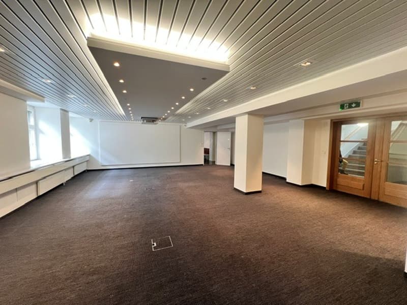 empty room, white walls, brown carpet, white ceiling, wooden door, windows, white pillars