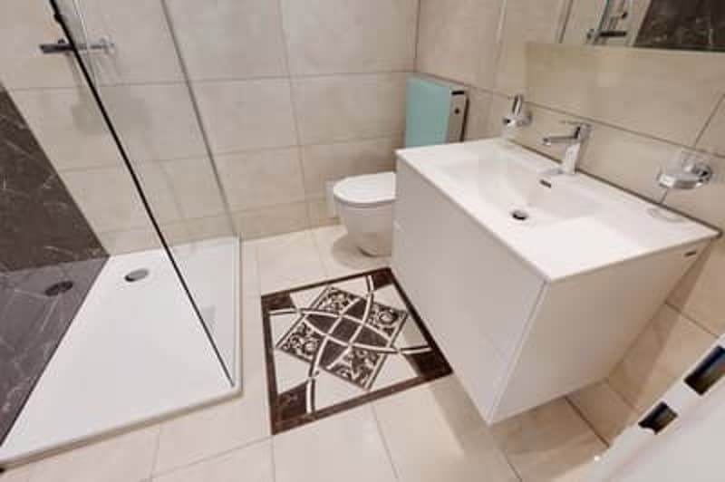 Modern bathroom, walk-in shower, white sink, toilet, grey tiled floor