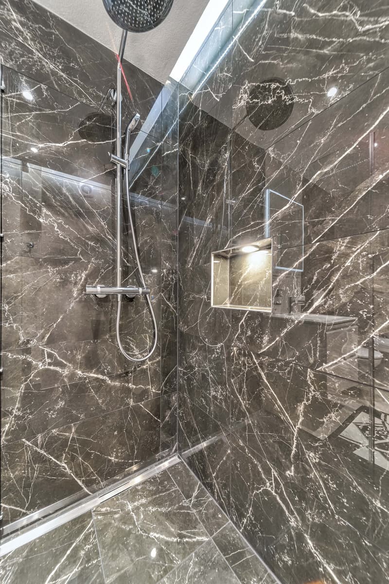 Bathroom with marble tiles, shower, glass enclosure, light fixtures