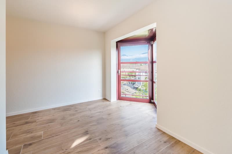 empty room with wooden flooring, white walls, open door leading to balcony, large windows