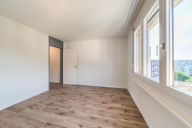 large room with wooden flooring, two glass doors, and large windows with views