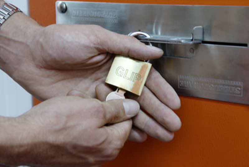 The image shows a person's hands holding a car key fob in front of a garage door or panel.
