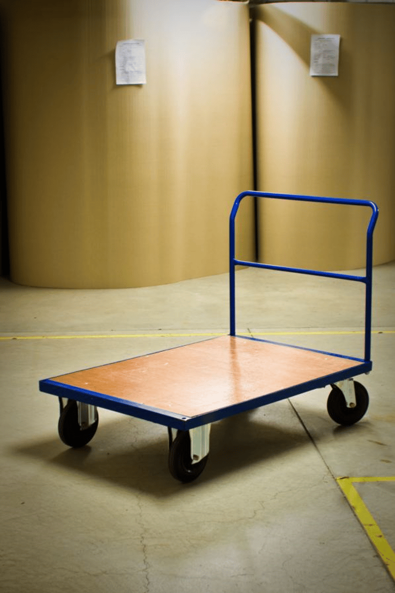 A blue metal utility cart with a wooden platform and wheels, standing on a concrete floor with yellow markings.