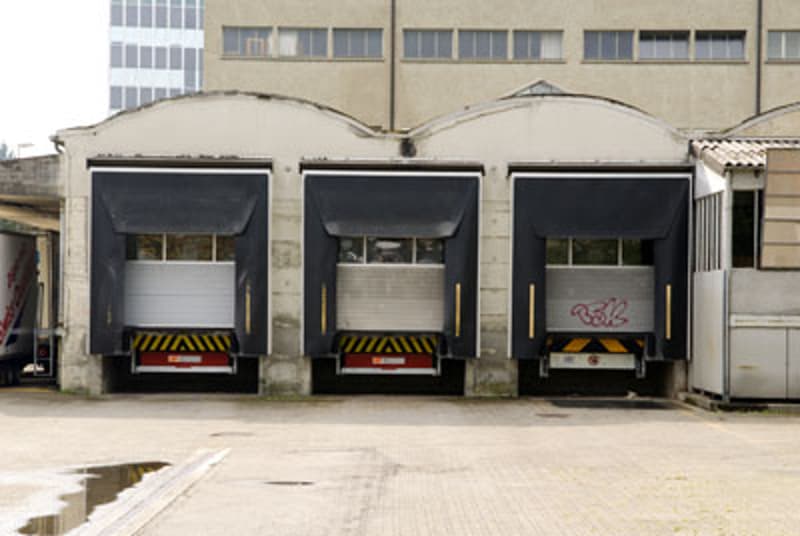A commercial building with three garage doors for vehicles to enter and exit.