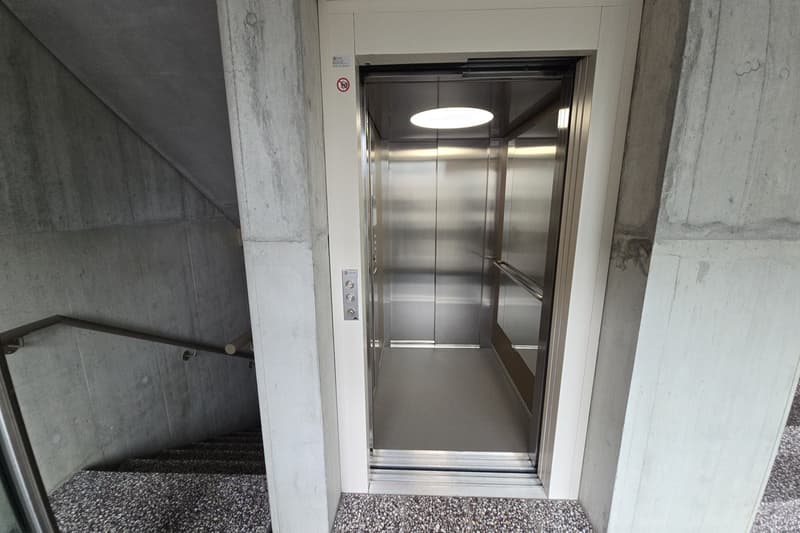 Elevator in building, modern design, stainless steel, glass doors, control panel.