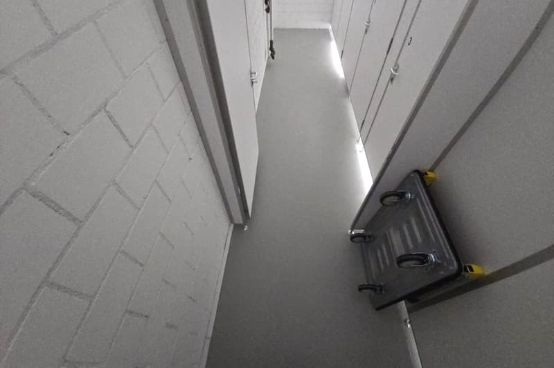 Car storage area with tiled walls, gray flooring, and trolley