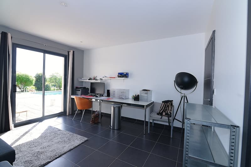 modern office with sliding glass door, desk, chair, computer, trash can, rug, shelves, lamp