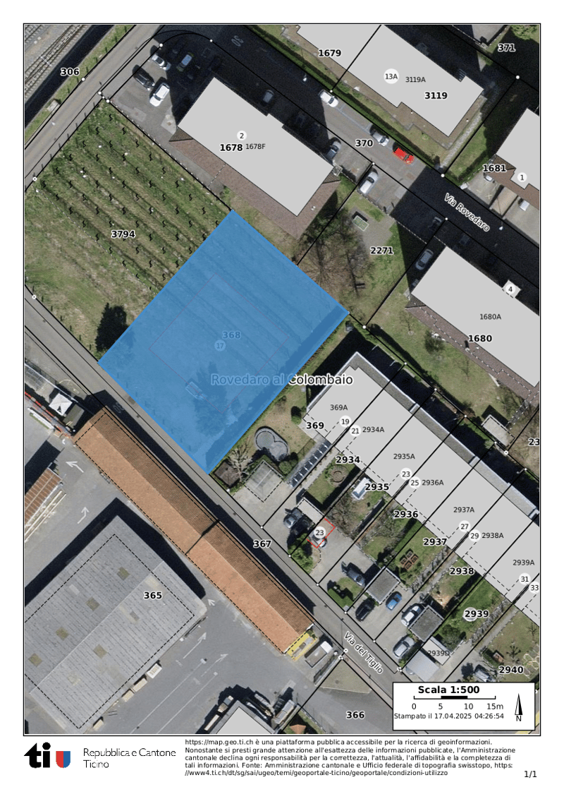 The image shows an aerial view of a residential area. There is a large blue building in the center of the image, surrounded by smaller residential buildings and parking spaces.