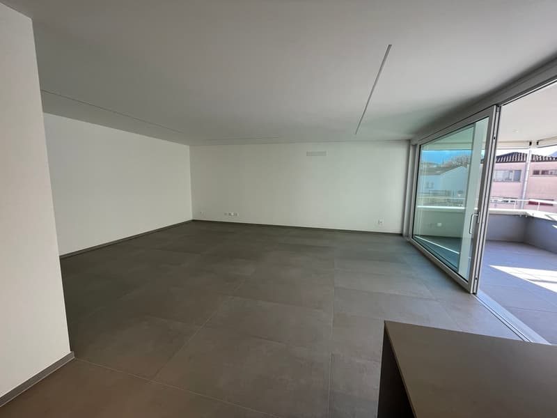 large room with tile flooring, white walls, sliding glass door to a balcony, power outlets