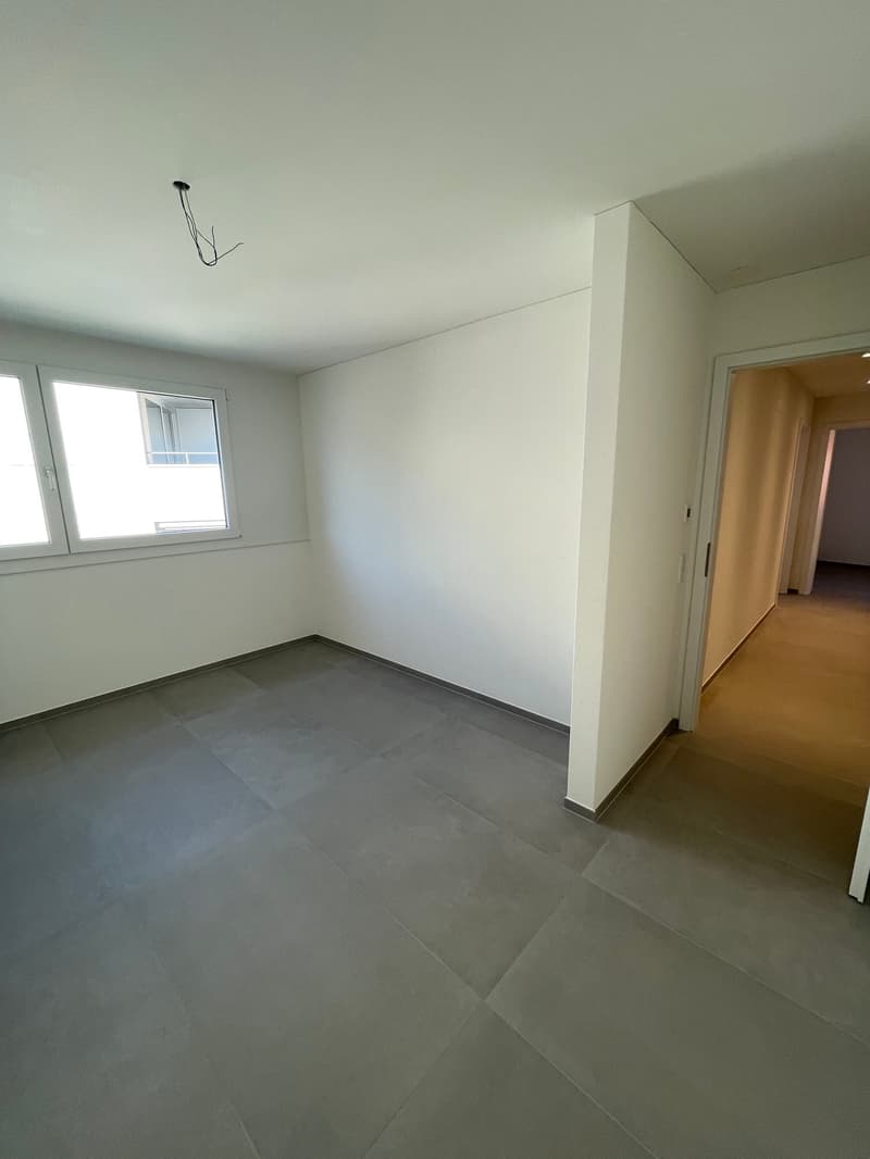 Empty room with a large window, white walls, and tiled floor