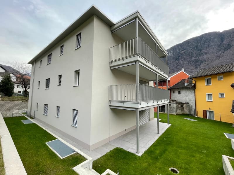 Two story building, light gray exterior, balcony on the upper floor, garden in front