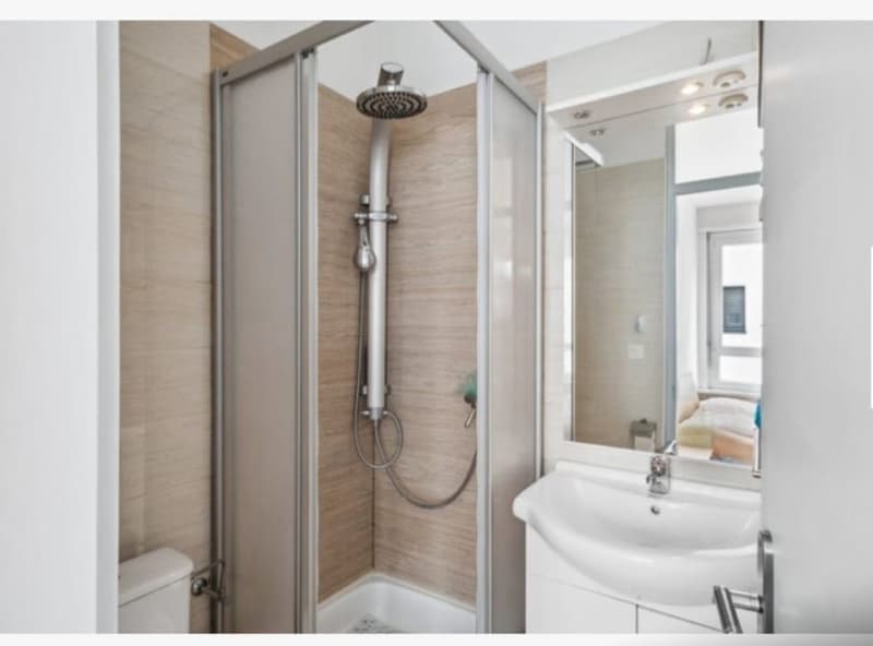 modern bathroom with shower enclosure, white sink, wooden paneling, large mirror, toilet