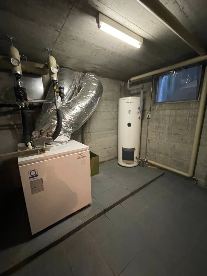 Basement with water heater and furnace, brick walls, tiled floor, window, storage box