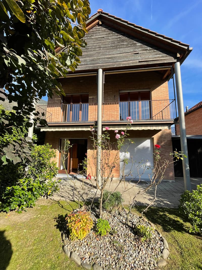 two story brick house, balcony, white garage door, plants, gravel driveway