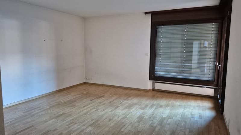 Empty room with white walls, hardwood floors, large window, and view of the outside