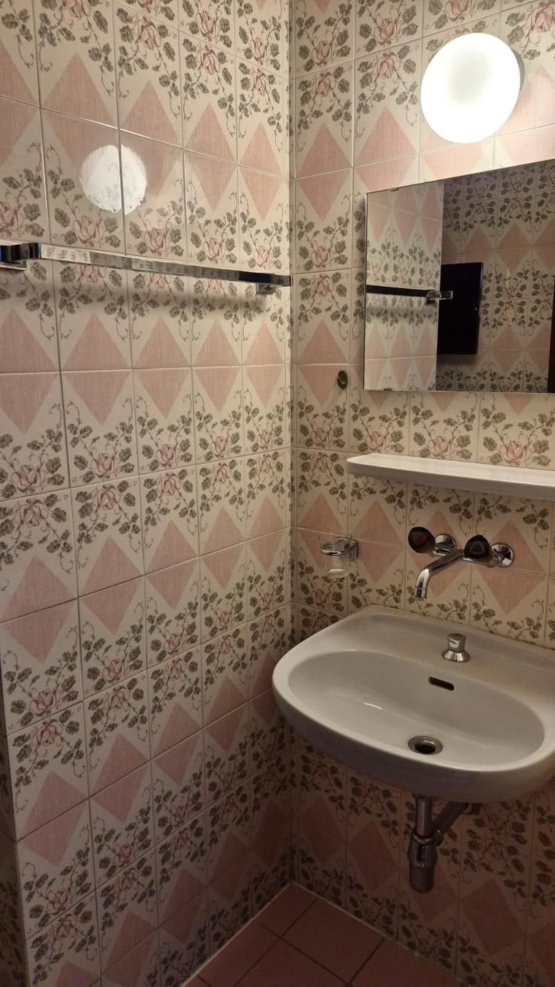 bathroom with sink, mirror, towel rack, tiles with floral patterns