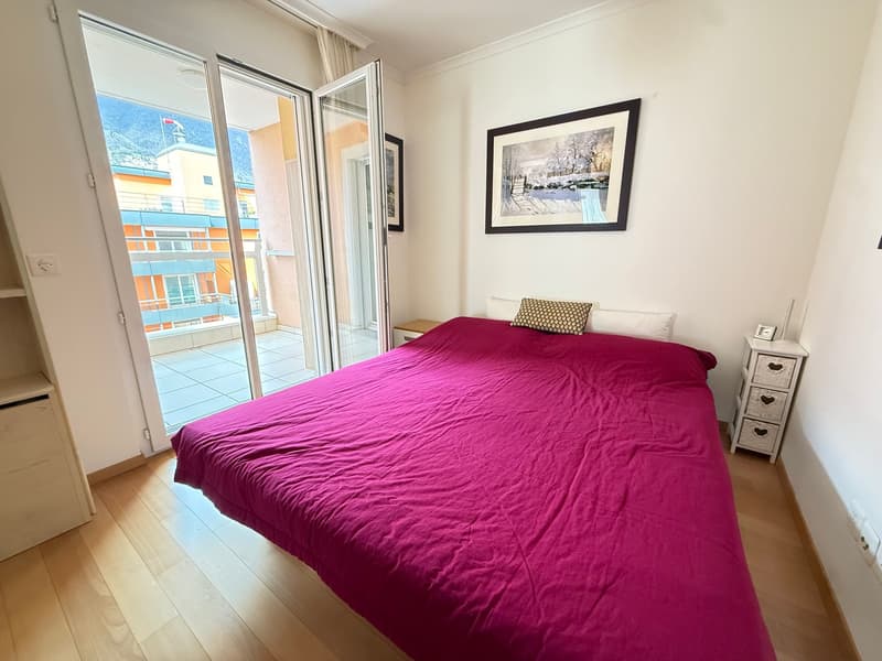 double bed, pink bedspread, bedside table, nightstand, picture frame, sliding glass door, balcony