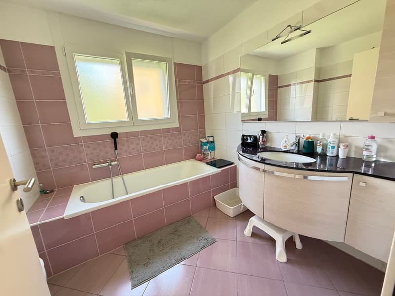 Bathroom with bathtub, sink, mirror, and tiled floor
