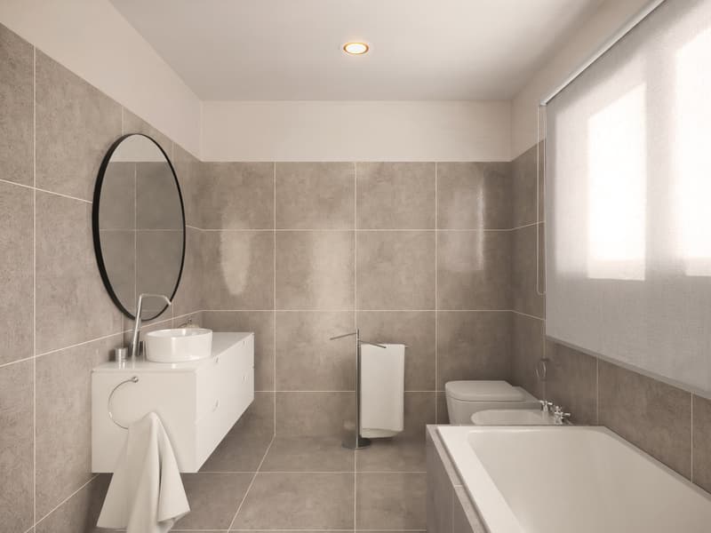 Bathroom with white bathtub, white sink, white cabinet, round mirror, white towels, white toilet, white tiles