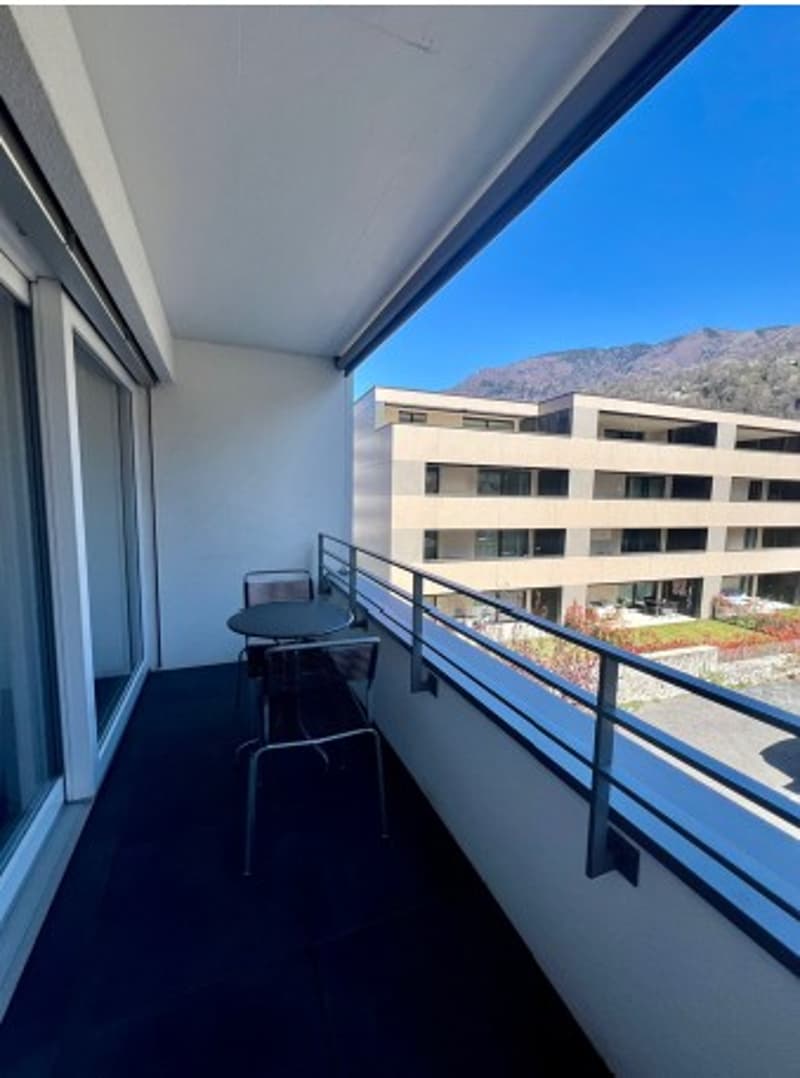 Balcony with table and chairs, glass doors, metal railing, view of mountains