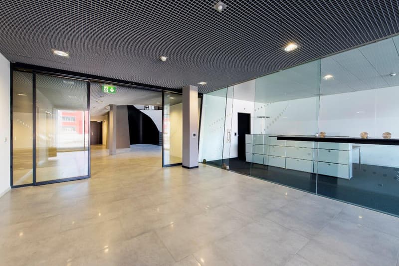 Glass walls, ceiling mounted lights, beige floor tiles, glass entrance doors