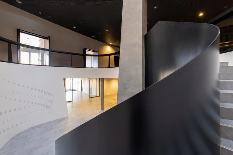 modern spiral staircase with black walls and grey flooring