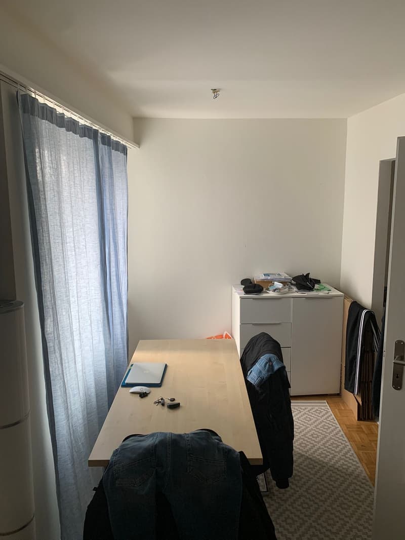 empty room with desk, cabinet, rug, and clothes
