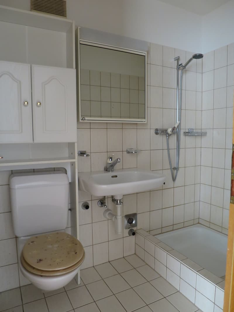 white tiled bathroom with toilet, sink, mirror, bathtub, and shower