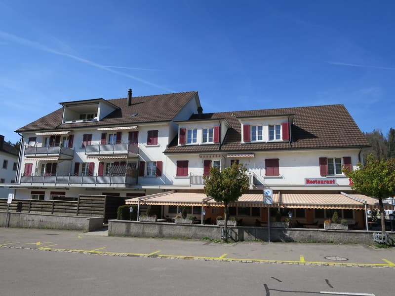 3 story building, brown roof, white walls, red shutters, balconies, restaurant