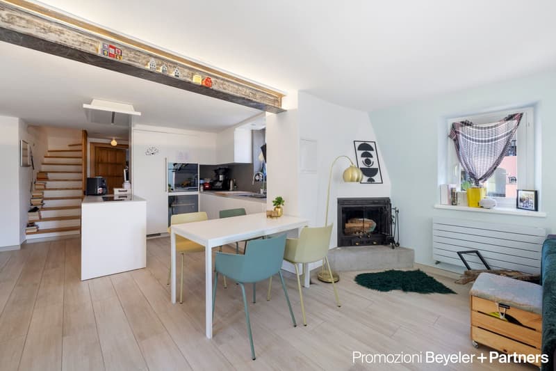 modern dining area with white dining table, wooden floors, white kitchen, stairs, fireplace